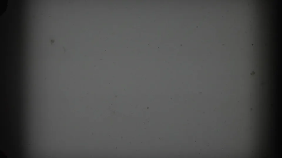 Soft, dark 8mm frame with visible dust and edge shading before the outdoor yard scene appears.