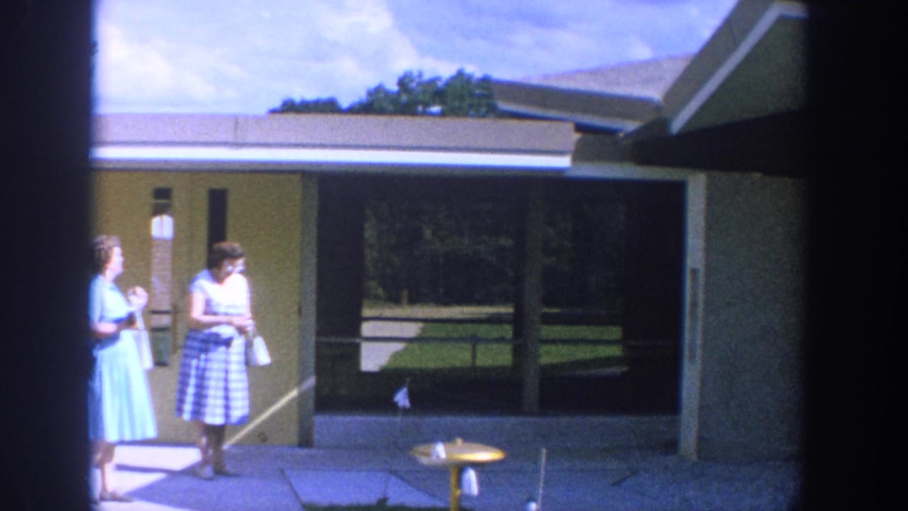 Two women stand near the church entrance, one holding a camera or small object.