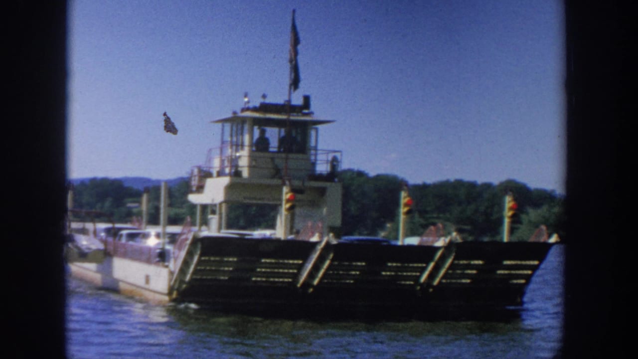 Vehicle ferry seen from the front with cars aboard and an American flag above the control tower.