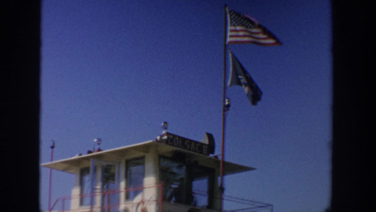 Close view of the ferry pilothouse with an American flag and another dark flag above it.