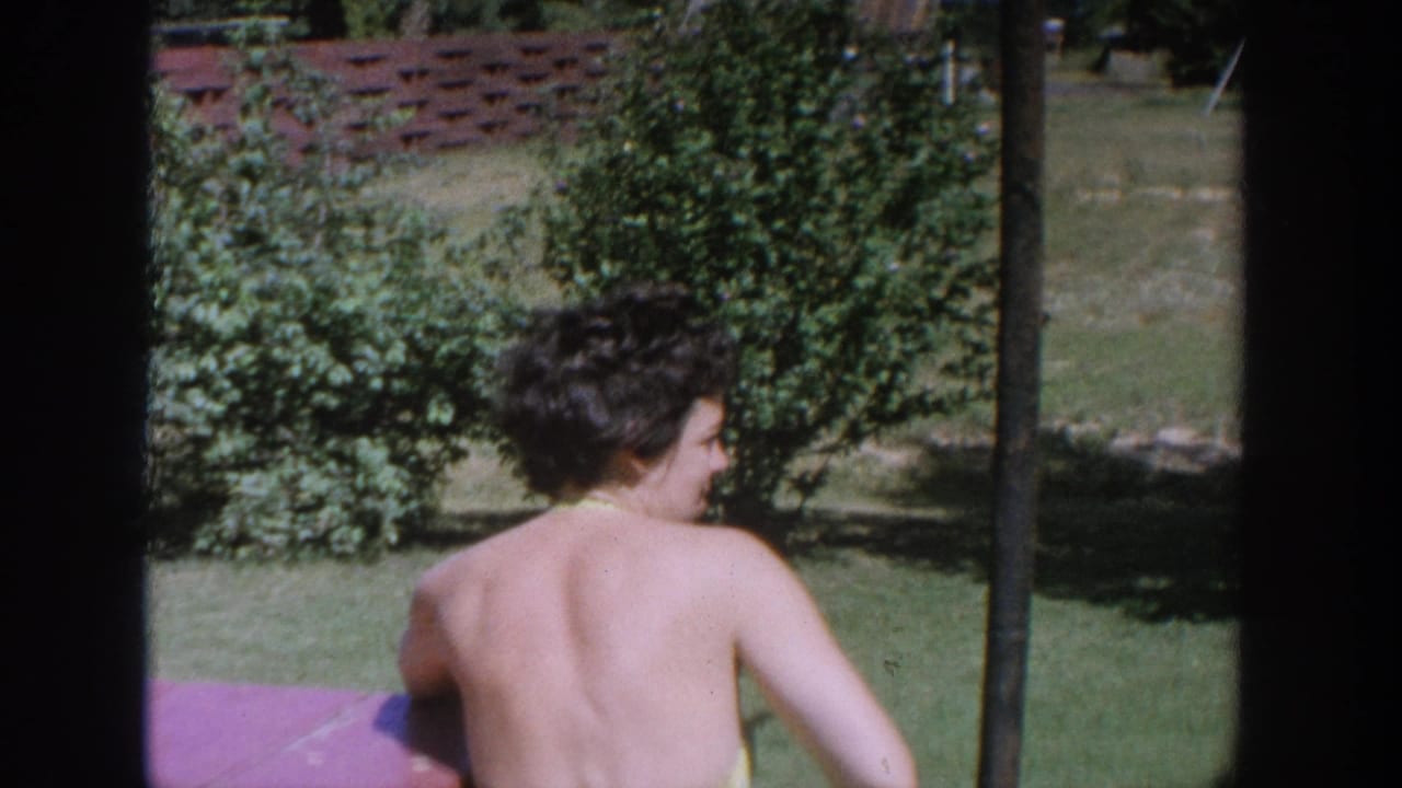 Woman seen from behind near a red picnic table in a grassy yard.
