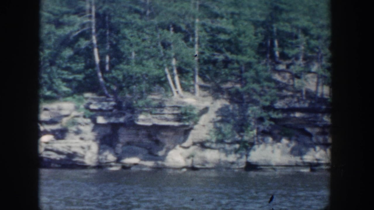 Layered rock cliff and trees reflected near the waterline.