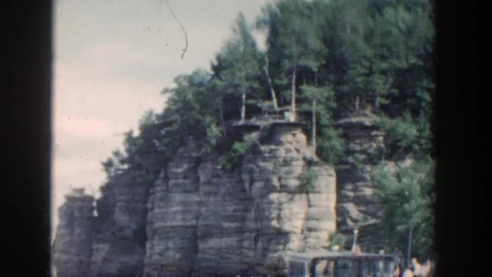 Wisconsin 1964 scenic frame showing stratified rock cliffs, trees, sky, and a railing at the lower edge.