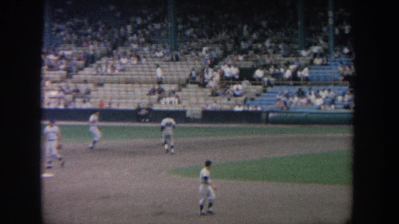 1964 New York home-movie frame of baseball players moving across the infield during warmups before a game.