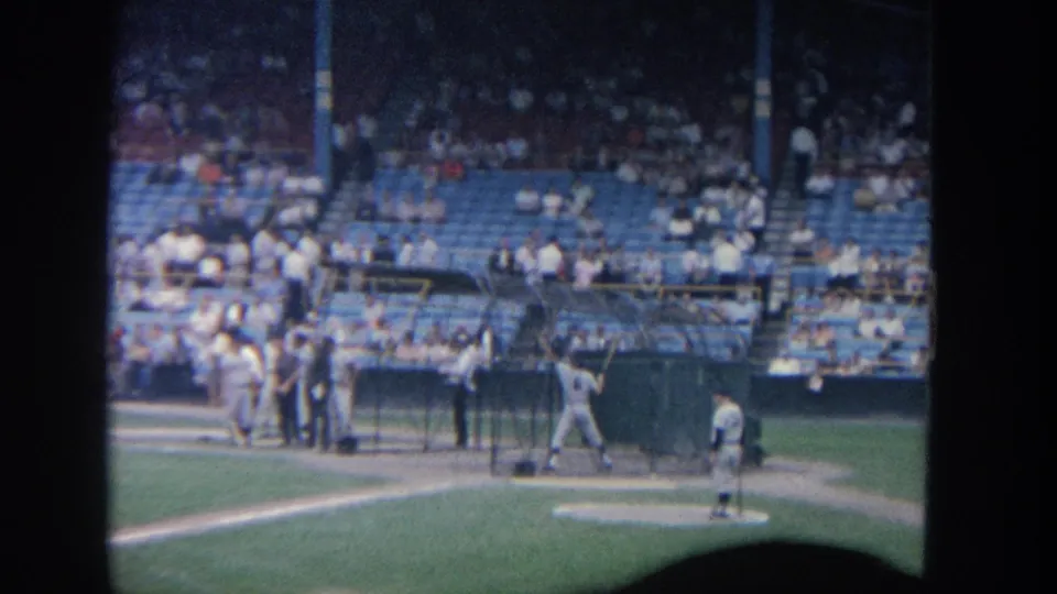 1964 New York baseball footage showing a batter near home plate, a pitcher on the mound, and spectators in blue seats.