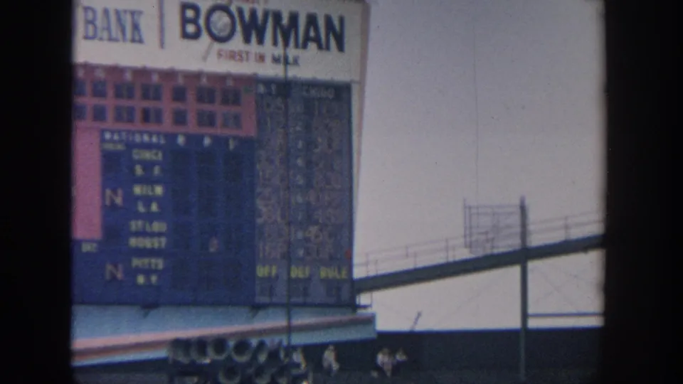Manual scoreboard at the 1964 New York baseball game, with team listings, inning boxes, and large commercial signage above it.