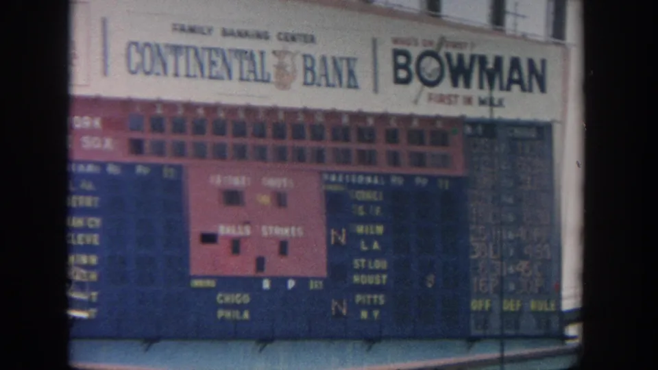 1964 New York stadium view showing a manual baseball scoreboard, blue seating, spectators, and Continental Bank and Bowman Gum signage.