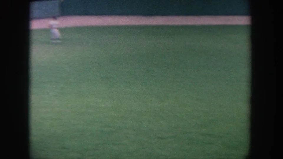 A distant player stands near the top edge of the outfield view in a brief, softly framed 1964 New York baseball shot.