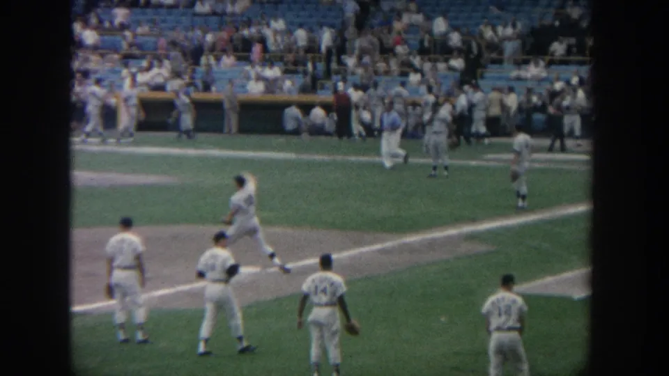 1964 New York baseball warmup scene with numbered players, gloves, infield dirt, grass, and seated spectators.