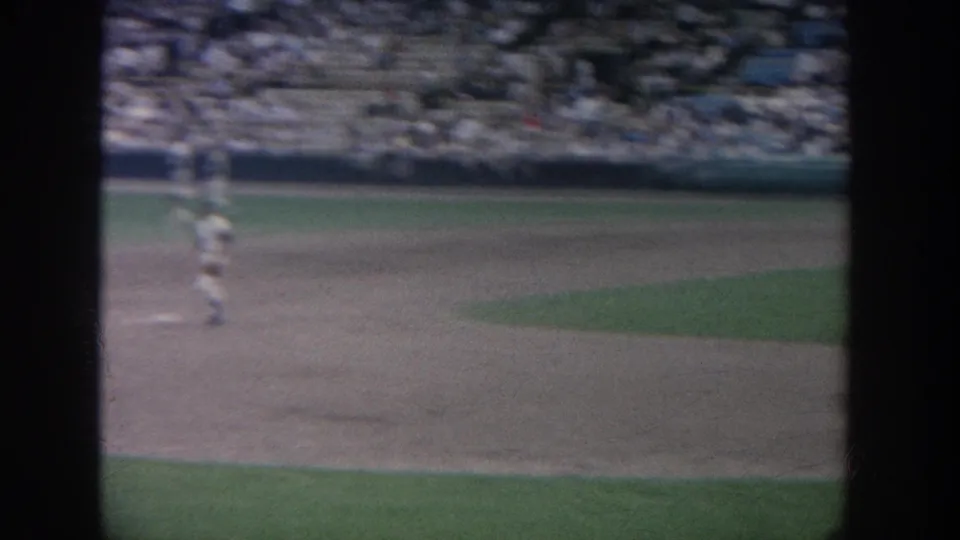 1964 New York baseball game footage showing the infield from a spectator angle, with a player at left and a crowded stand in the background.