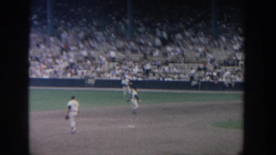 1964 New York baseball footage showing a white-uniformed player moving on the infield after a ground ball play, seen from the stands.