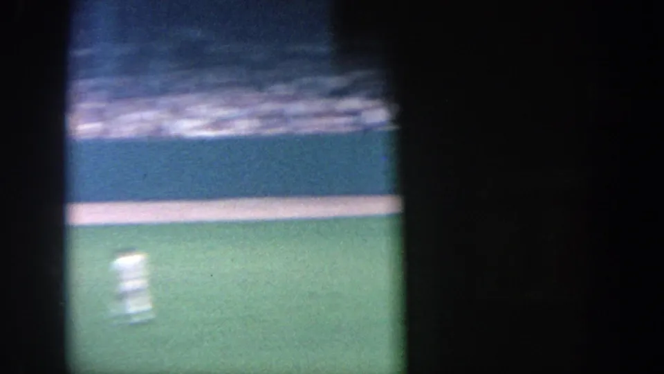 1964 New York 8mm frame with a motion-blurred player on the field below crowded stadium seating.
