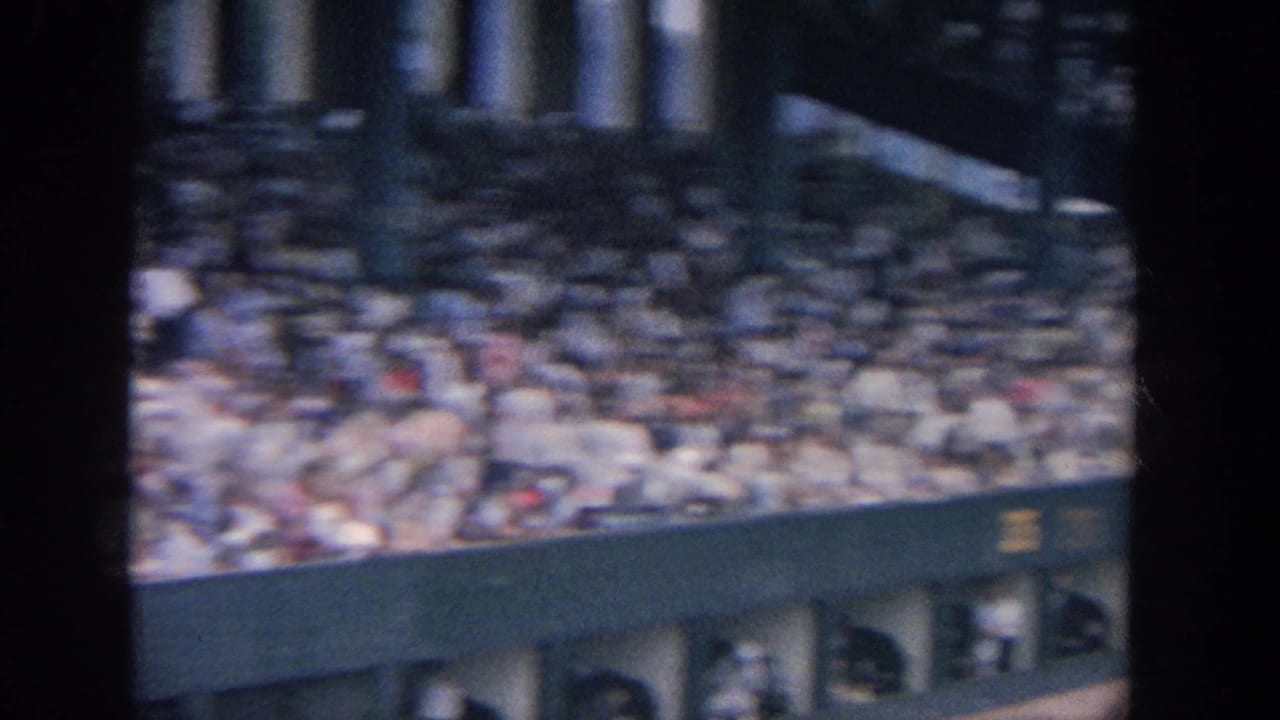Blurred view of stadium seating and structure above a green wall.