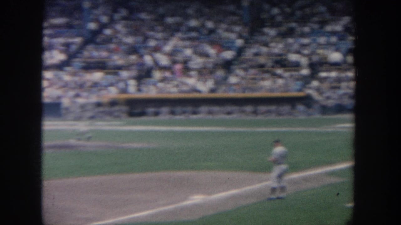 Infielder stands near a base on the dirt while the crowd fills the background.