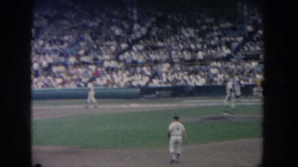 Wide spectator-shot view across the infield, showing multiple uniformed players and crowded stands in the supplied 1964 New York baseball footage.