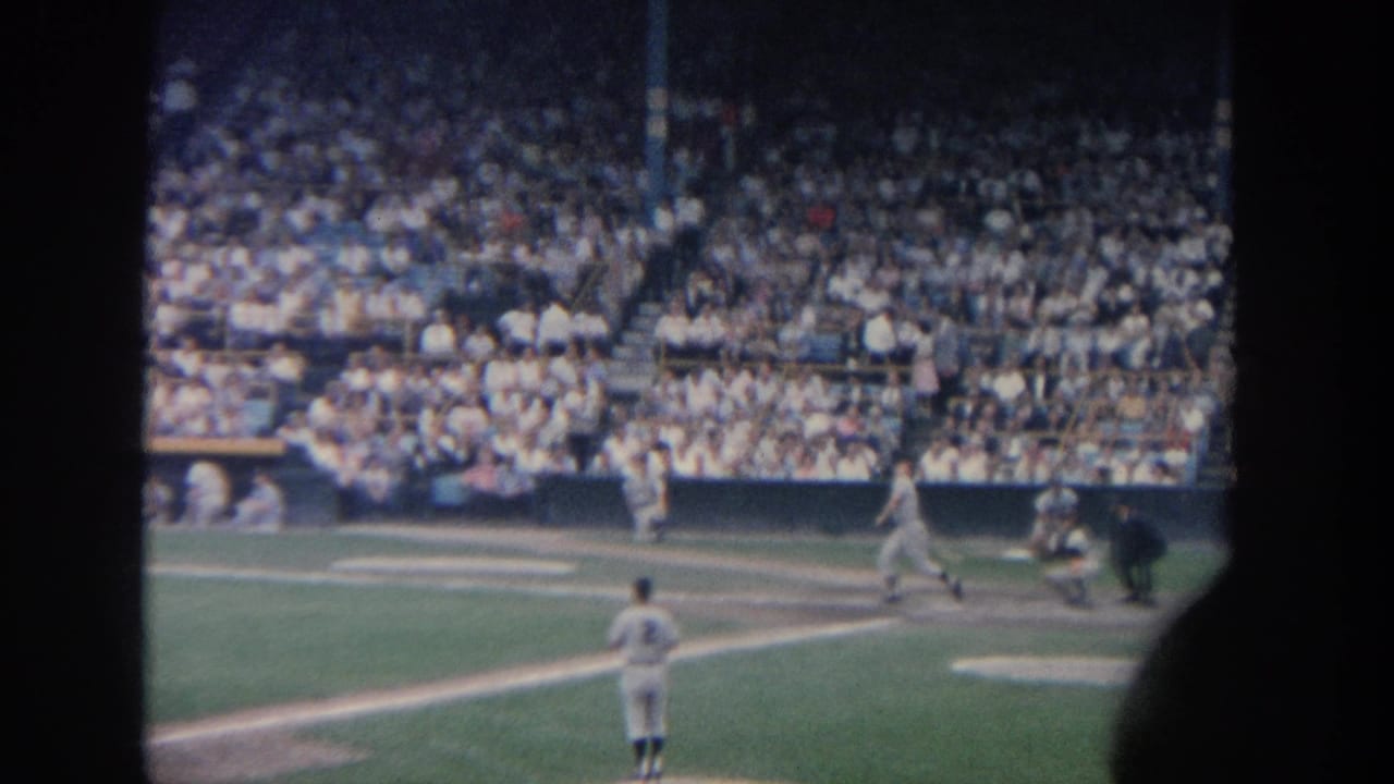 Batter swings as the catcher and umpire watch from behind home plate.