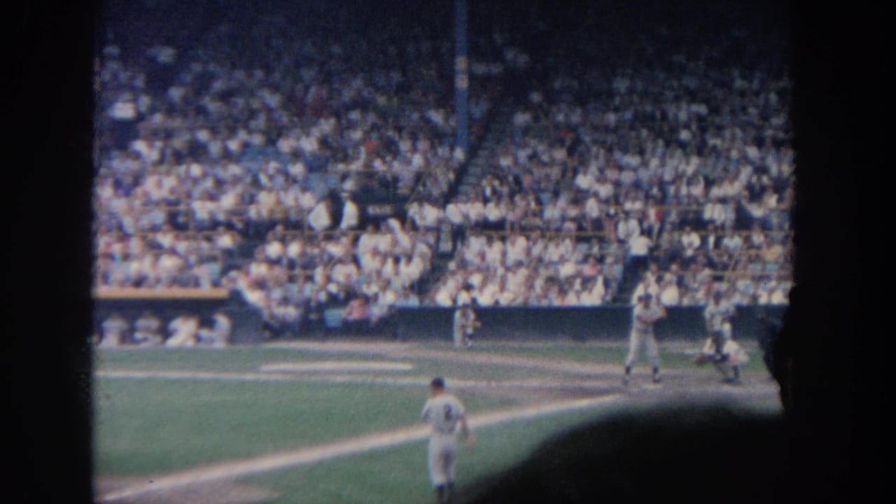 Baseball play near home plate with a runner or batter moving as the crowd fills the background.