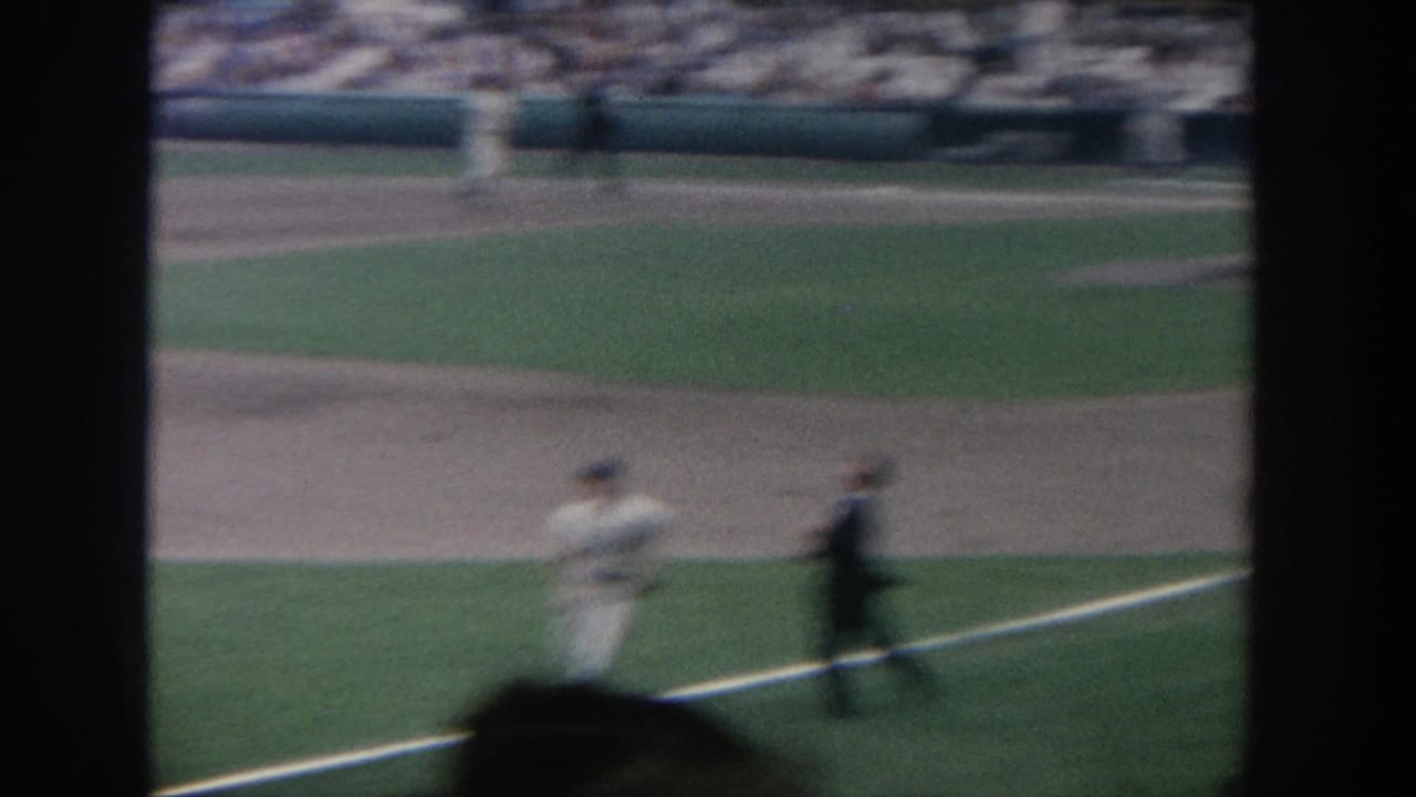 1964 New York 8mm baseball footage showing a soft-focus spectator view of players near the infield foul line.