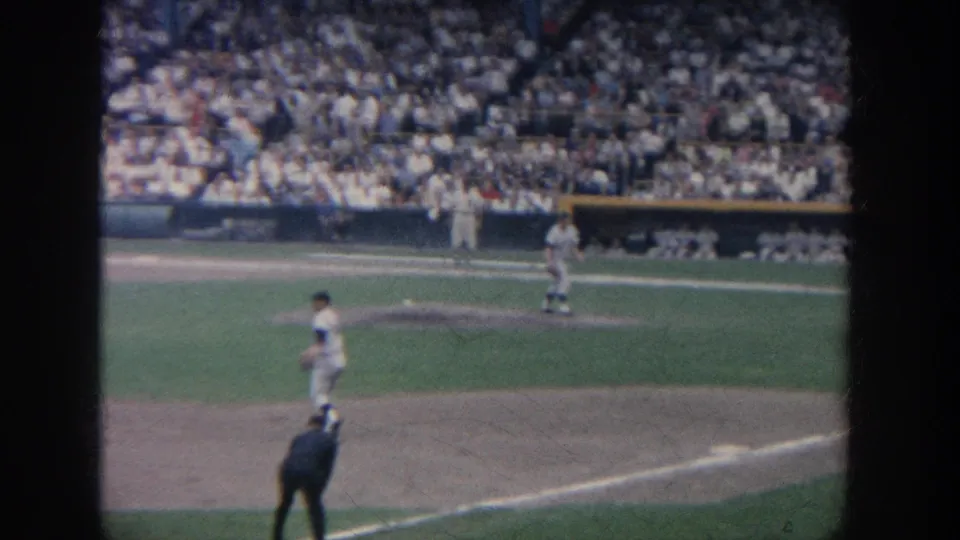 1964 New York 8mm frame showing players spread across the infield while the stadium crowd watches from the stands.