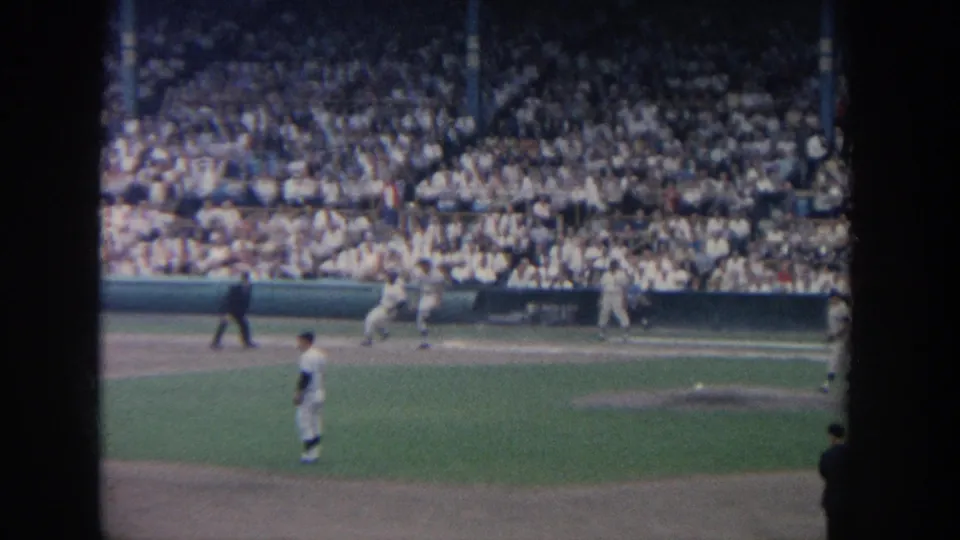 1964 New York baseball game viewed from the stands, with players on the field and a dense crowd in the background.