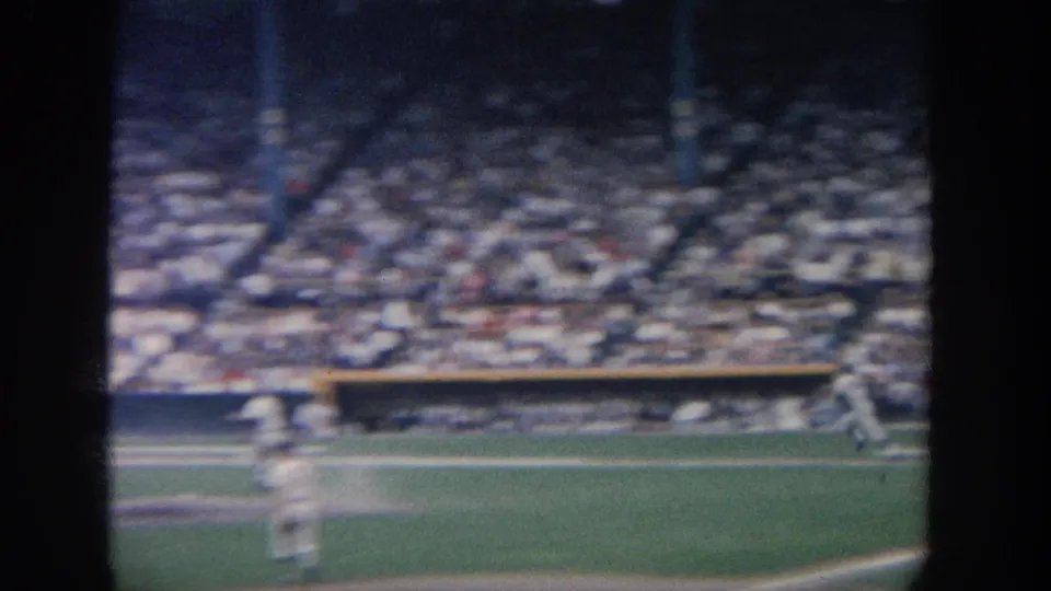 Soft 8mm frame of baseball action in New York, with a player moving across the field before packed grandstands.
