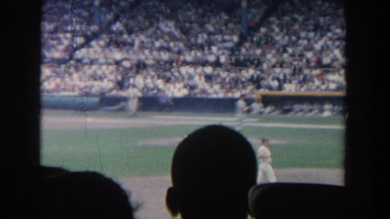 Baseball player on the field with a packed stadium crowd behind him.