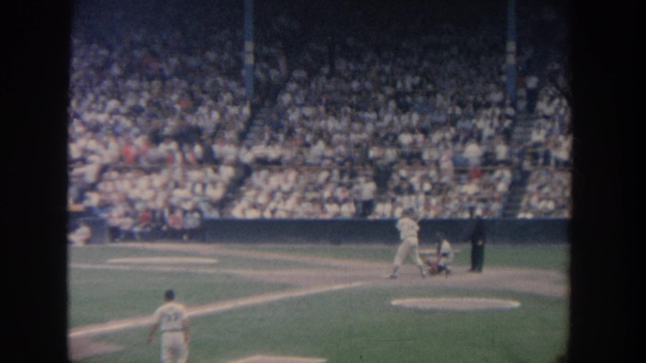 Batter, catcher, and umpire at home plate with a large crowd in the stands.