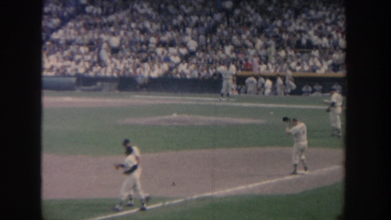 A batter stands near home plate while another player moves across the infield.