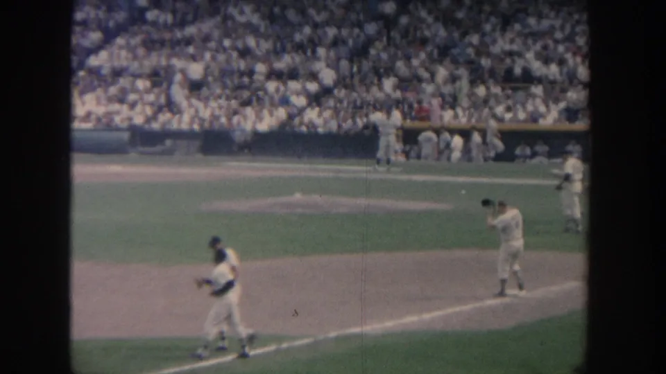 Fan-shot 1964 New York baseball frame with a batter at the plate, an infield player, mound area, and crowded stands.
