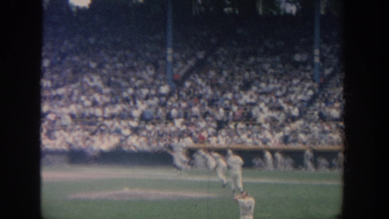 1964 New York 8mm footage appears to show a baseball game with players in white uniforms and a dense crowd in the stands.