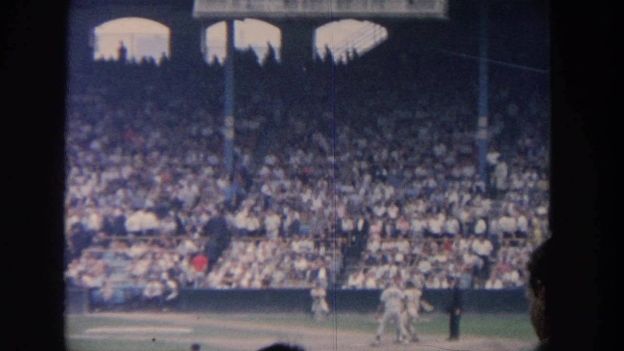 Baseball players on the infield with a batter beginning to run and crowd in the stands.