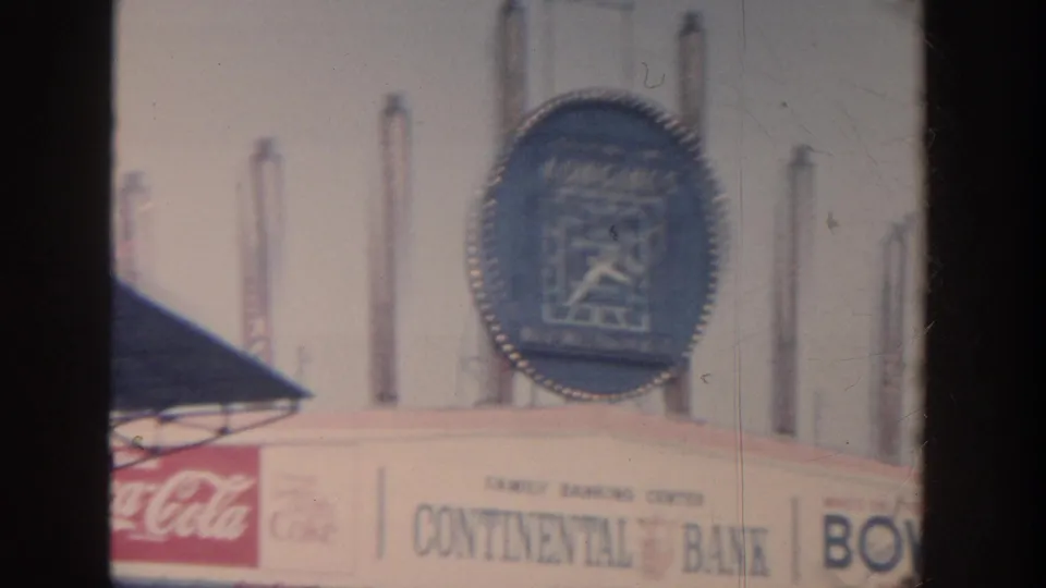 1964 New York ballpark detail showing a Longines clock, Coca-Cola branding, and Continental sign elements filmed from the stands.