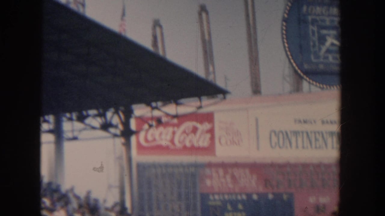 Stadium signage with Coca-Cola advertising, a Continental Bank sign, and a blue Longines clock partly blocked by a dark foreground shape.