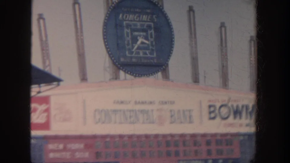 1964 New York stadium signage with a large blue Longines clock, Coca-Cola panel, Continental Bank lettering, and partial Bowlers sign visible above the field.