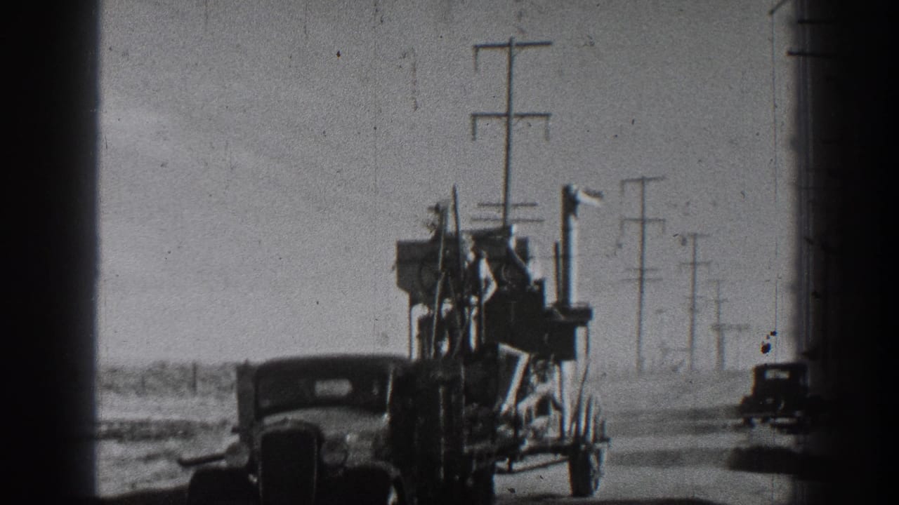 A classic automobile pulls a cargo-packed trailer on a California rural road, with utility poles receding into the distance.