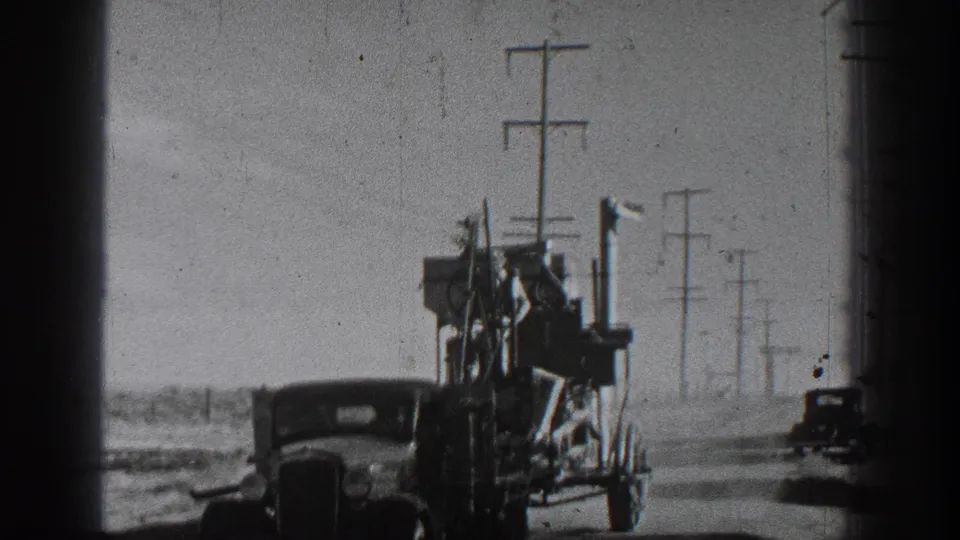 A classic automobile pulls a cargo-packed trailer on a California rural road, with utility poles receding into the distance.