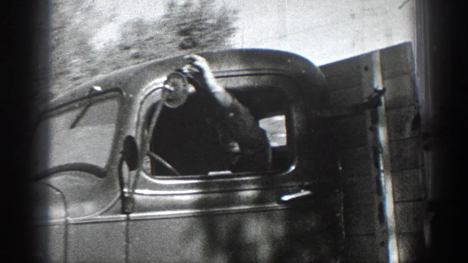 Close 1936 California view of a classic truck cab, with a person partly visible near the side window and roadside terrain beyond.