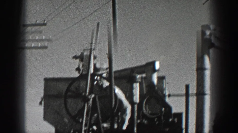 A worker appears beside upright truck-mounted machinery on a rural California roadside, with poles and overhead wires in view.