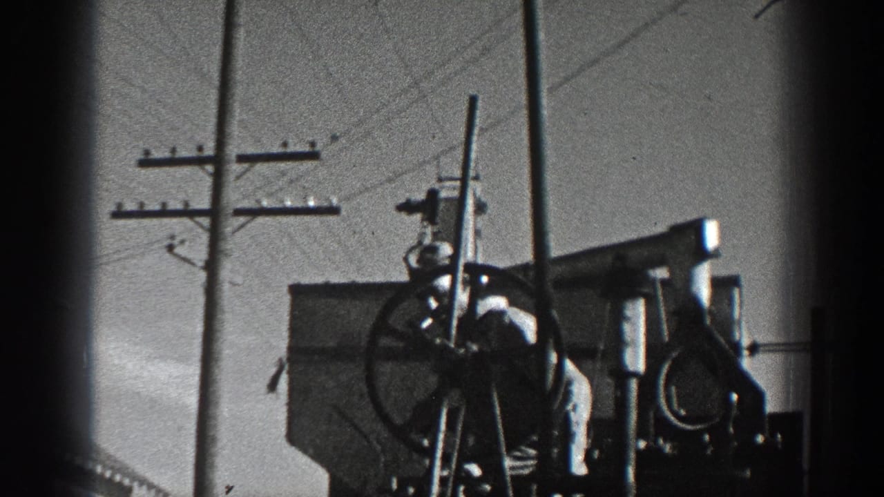 1936 California 8mm frame showing a large industrial wheel mechanism beside utility poles and overhead wires.