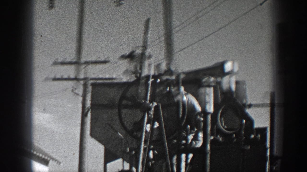 A person stands or works near heavy wheel machinery in 1936 California black-and-white home-movie footage.