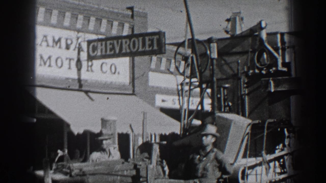 Lampa Chevrolet Motor Co. sign above cars and men standing in a service or dealership area.