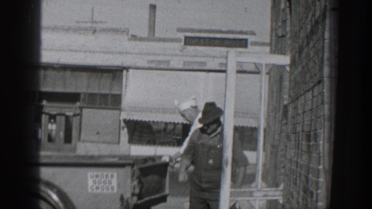 1936 California 8mm frame showing two men beside a truck in an alley, with storefront windows, an awning, and an UNDER 5000 GROSS sign visible.