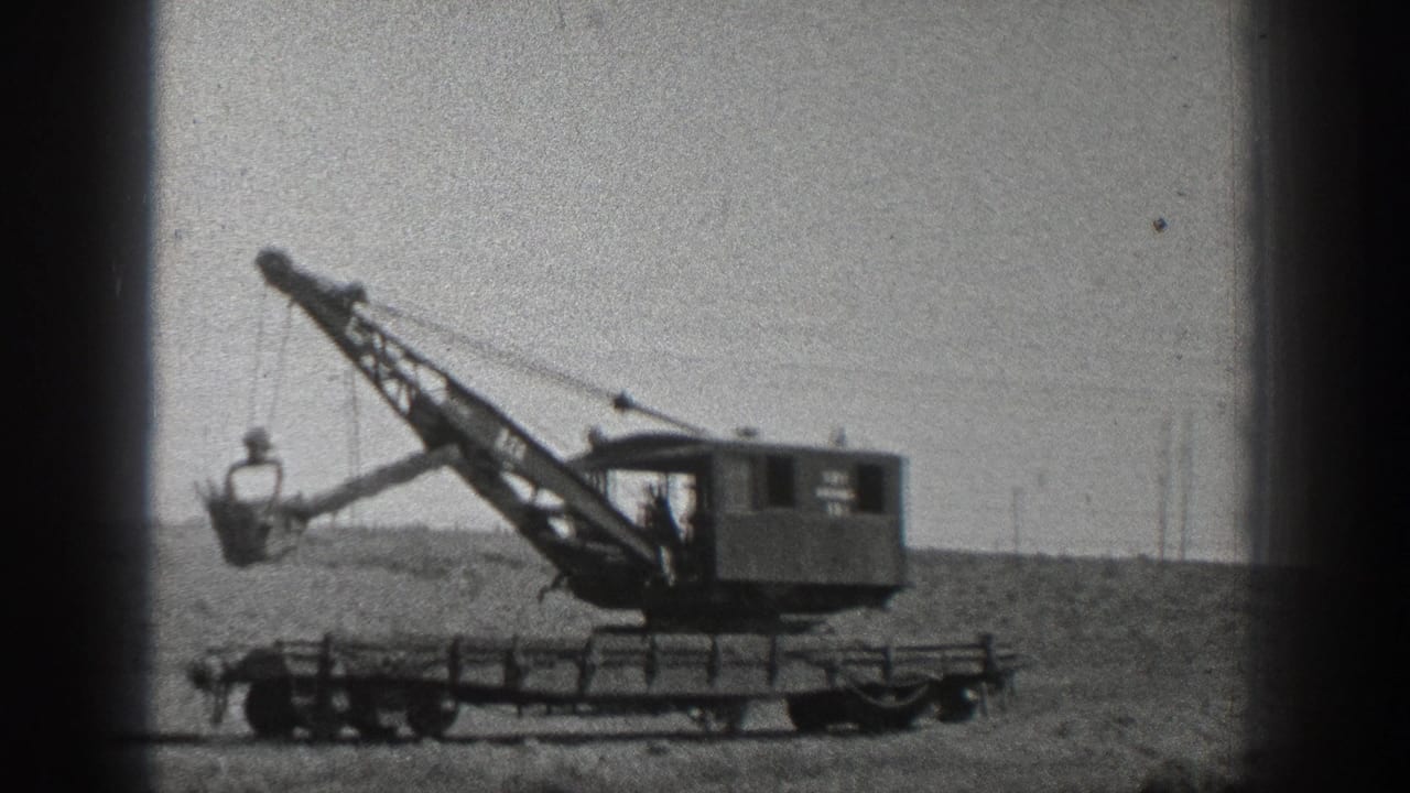 1936 California 8mm frame showing a wheeled industrial crane with its bucket extended over a dirt field.