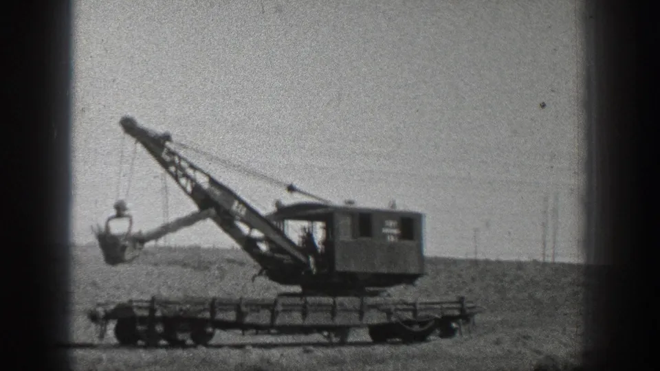 1936 California 8mm frame showing a wheeled industrial crane with its bucket extended over a dirt field.