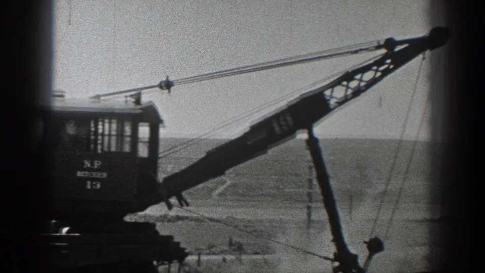 1936 California 8mm frame showing a marked rail crane with its boom extended over open terrain.