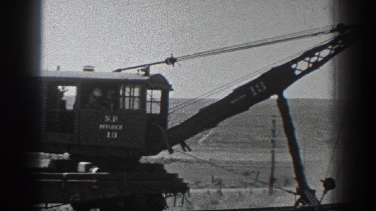 Side view of a marked crane cab and boom on railway tracks.