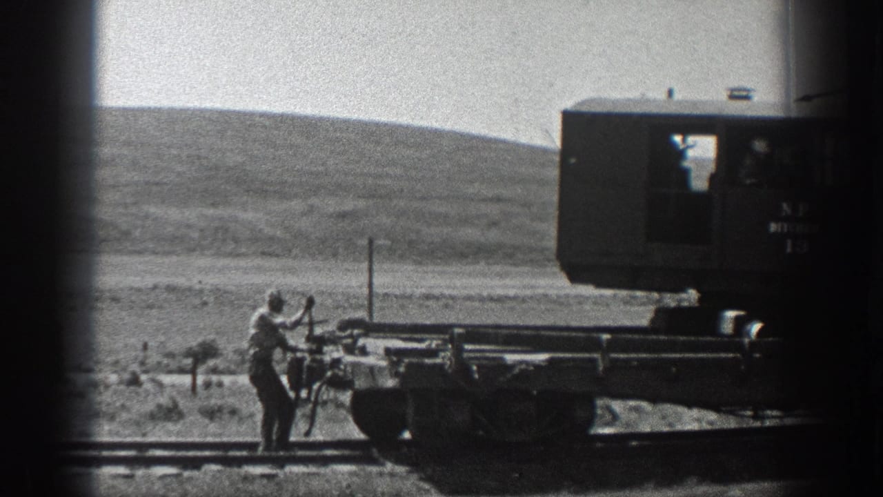 Black-and-white 1936 California home-movie frame of a worker handling rail equipment on open rural track.