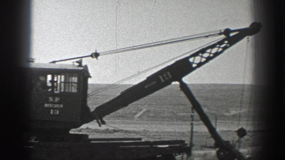 1936 California 8mm frame showing a small rail crane, its boom marked 13, with a person partly visible near the equipment.