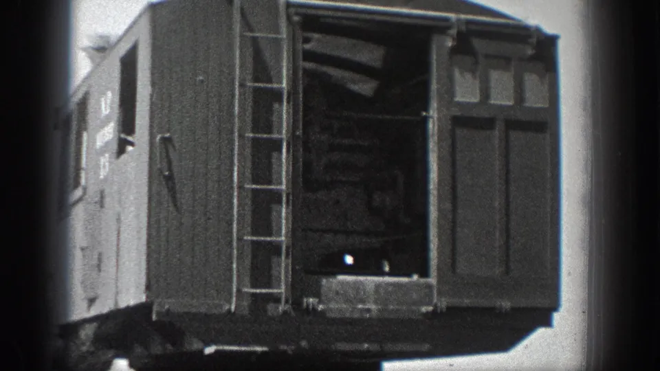 Close 8mm view of a wooden railcar in California, with ladder, open doorway, and partial lettering visible on the side.