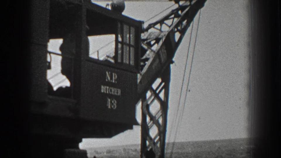 Side view of the N.P. DITCHER 13 crane cab and lattice boom over an open California field in 1936 footage.
